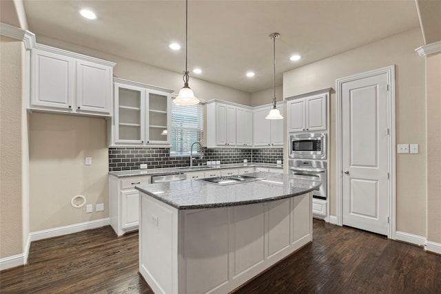 kitchen with a kitchen island, light stone counters, dark hardwood / wood-style flooring, white cabinets, and appliances with stainless steel finishes