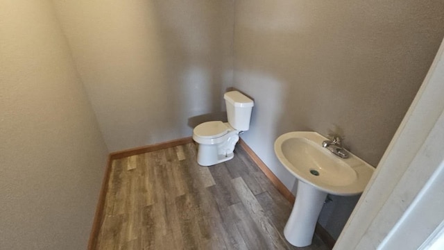 bathroom featuring baseboards, toilet, and wood finished floors