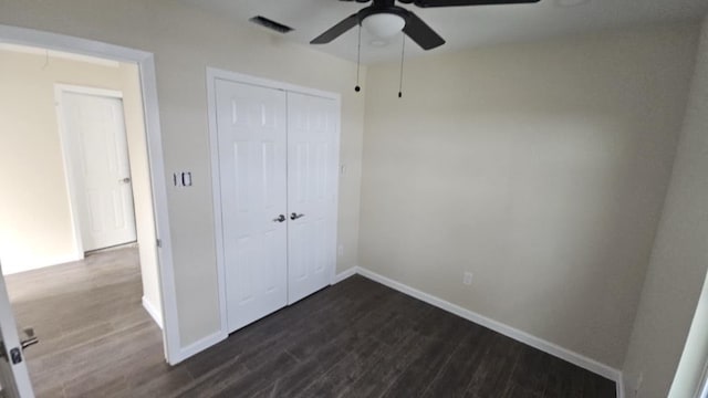 unfurnished bedroom with a closet, visible vents, dark wood-type flooring, ceiling fan, and baseboards