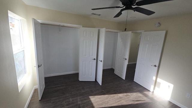 unfurnished bedroom featuring multiple windows, wood finished floors, and baseboards