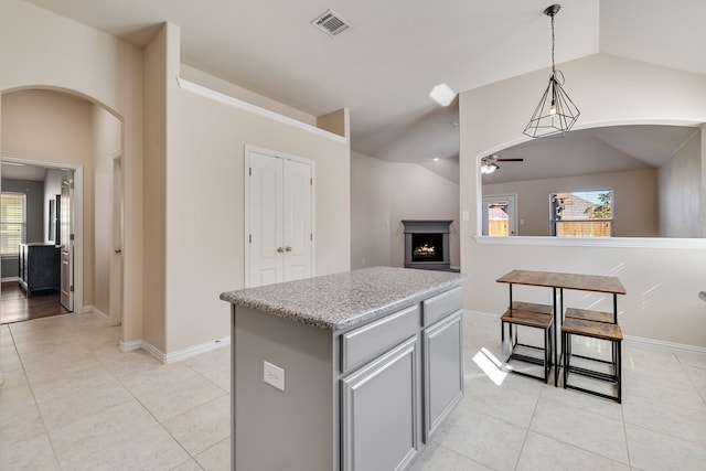 kitchen featuring a center island, decorative light fixtures, vaulted ceiling, and a healthy amount of sunlight