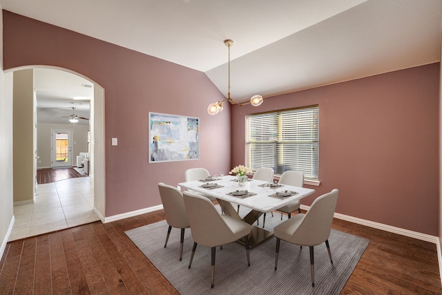 dining space featuring ceiling fan with notable chandelier, dark hardwood / wood-style floors, and lofted ceiling