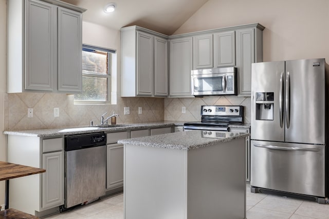 kitchen with a center island, backsplash, lofted ceiling, light tile patterned floors, and appliances with stainless steel finishes