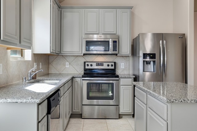 kitchen with light stone counters, gray cabinetry, stainless steel appliances, sink, and light tile patterned floors