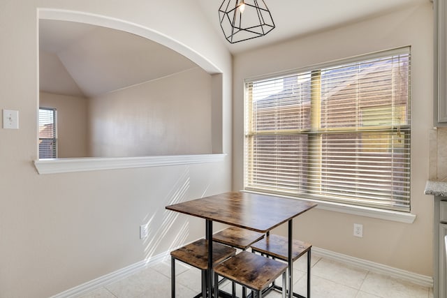 tiled dining space featuring plenty of natural light and lofted ceiling