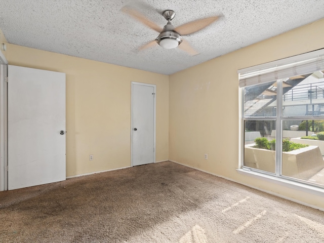 carpeted spare room with a textured ceiling and ceiling fan