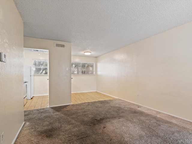 carpeted empty room with a textured ceiling