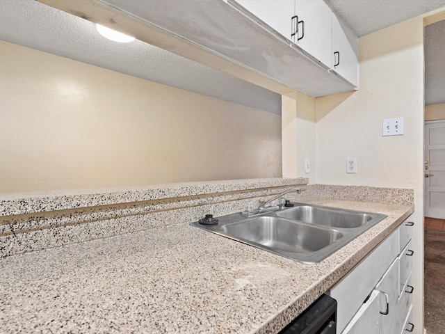 kitchen featuring a textured ceiling, sink, and white cabinets