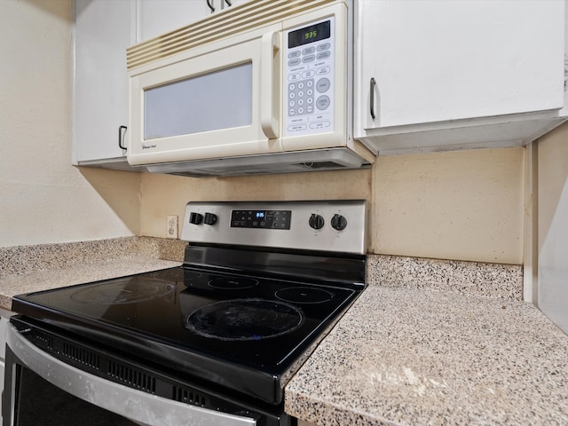 kitchen with light stone countertops, white cabinets, and stainless steel electric stove