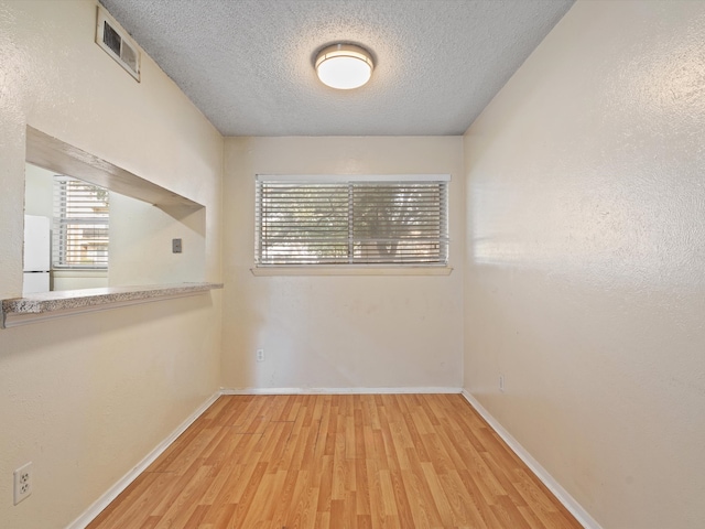 spare room with a textured ceiling and hardwood / wood-style flooring