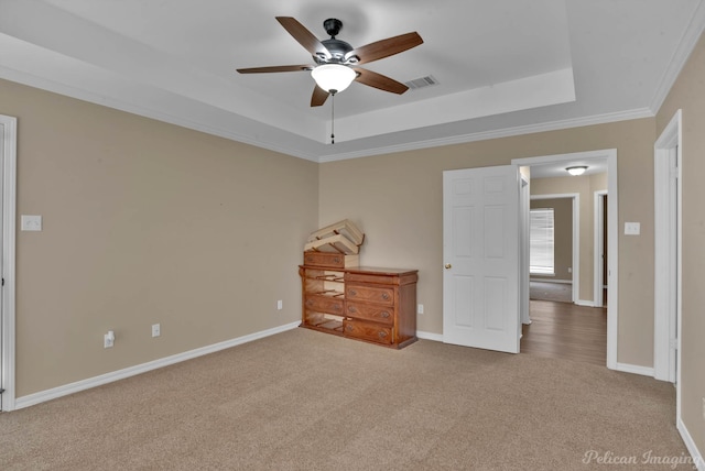 unfurnished bedroom featuring ornamental molding, carpet, a raised ceiling, and ceiling fan