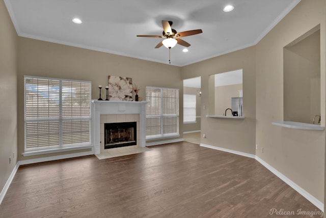 unfurnished living room featuring ornamental molding, wood-type flooring, a tile fireplace, and ceiling fan