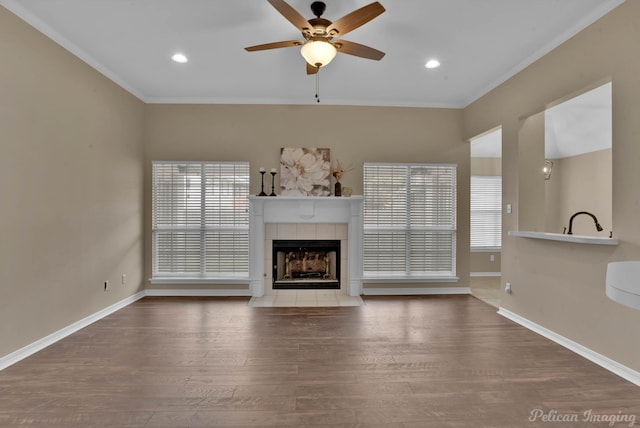 unfurnished living room with crown molding, wood-type flooring, a fireplace, and ceiling fan