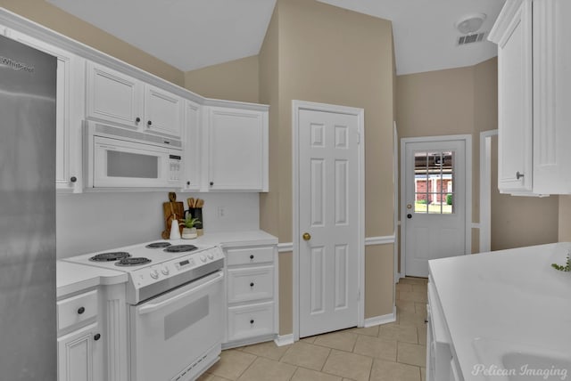 kitchen with white cabinetry, light tile patterned floors, and white appliances