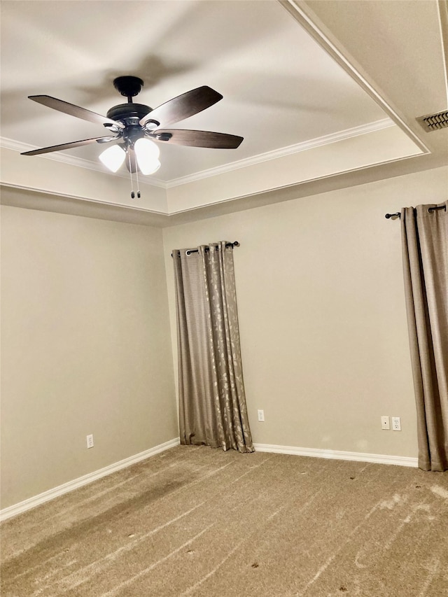 empty room with a raised ceiling, ceiling fan, and ornamental molding