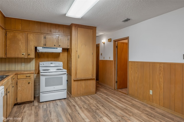 kitchen featuring light hardwood / wood-style floors, a textured ceiling, white appliances, and wood walls