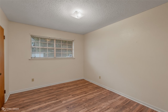 spare room featuring hardwood / wood-style floors and a textured ceiling