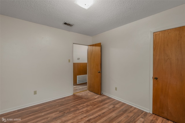 unfurnished room featuring a textured ceiling and wood-type flooring