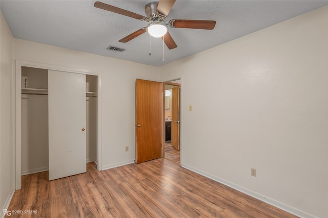 unfurnished bedroom with a closet, a textured ceiling, hardwood / wood-style flooring, and ceiling fan