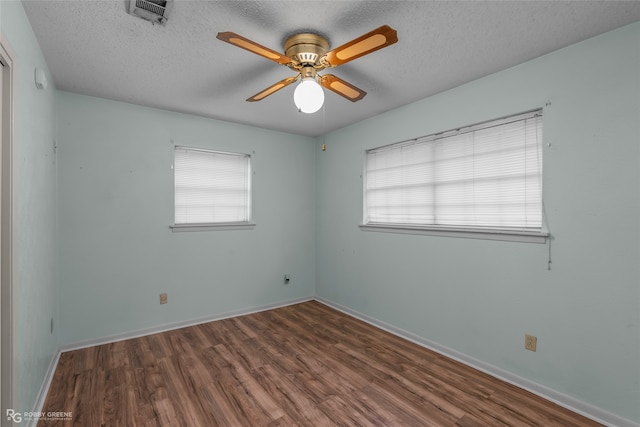 spare room with a textured ceiling, dark hardwood / wood-style floors, and ceiling fan