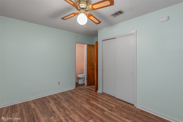 unfurnished bedroom with a closet, hardwood / wood-style floors, a textured ceiling, ensuite bathroom, and ceiling fan