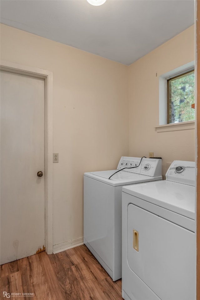 laundry room featuring independent washer and dryer and light hardwood / wood-style flooring