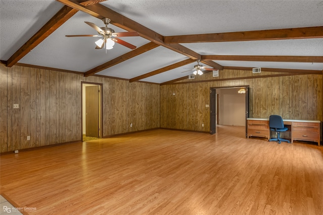 interior space with light hardwood / wood-style flooring, wood walls, built in desk, and a textured ceiling