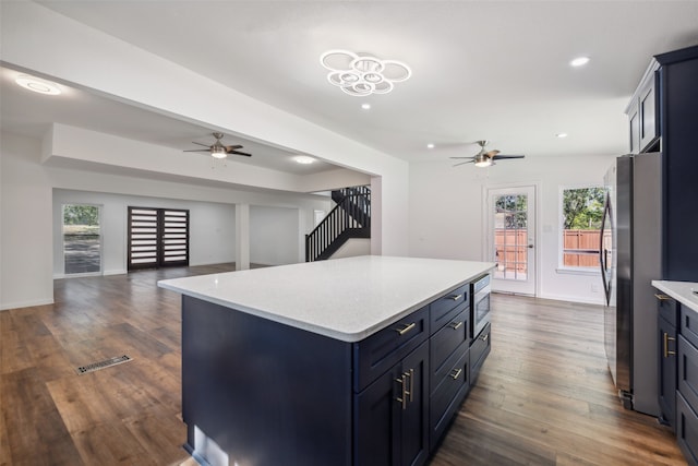 kitchen with appliances with stainless steel finishes, a center island, a wealth of natural light, and dark hardwood / wood-style flooring