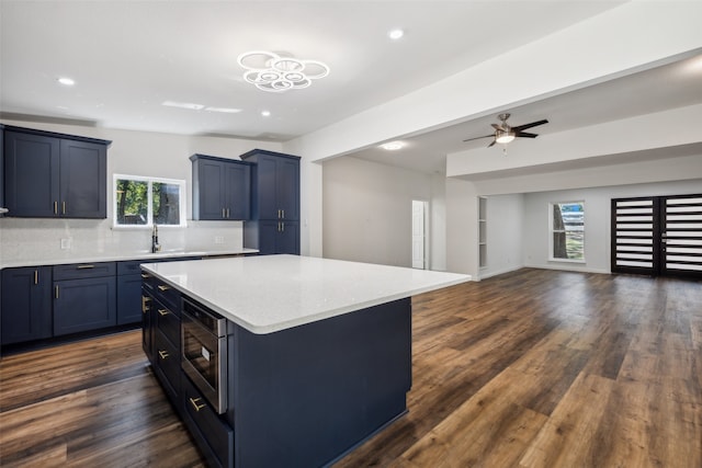 kitchen featuring stainless steel microwave, decorative backsplash, dark wood-type flooring, and a kitchen island