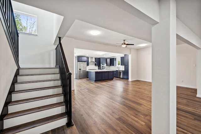 stairs featuring wood-type flooring and ceiling fan