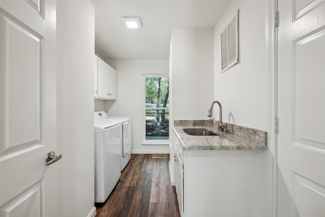 clothes washing area with sink, washer and dryer, cabinets, and dark hardwood / wood-style flooring