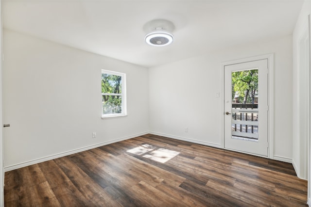 empty room with a healthy amount of sunlight and dark hardwood / wood-style flooring