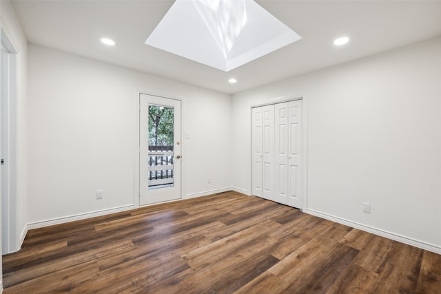 unfurnished bedroom featuring dark hardwood / wood-style floors, a closet, and a skylight