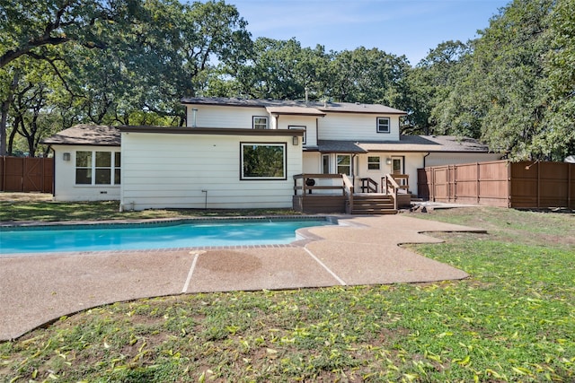 rear view of house featuring a pool side deck and a lawn