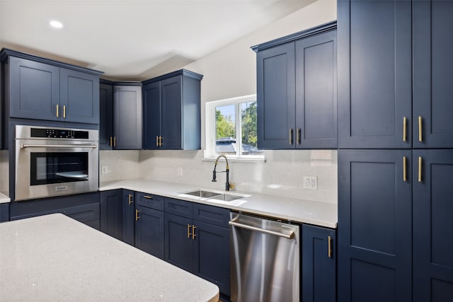 kitchen with decorative backsplash, stainless steel appliances, sink, blue cabinets, and light stone counters