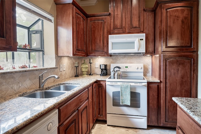 kitchen with sink, decorative backsplash, light stone counters, and white appliances