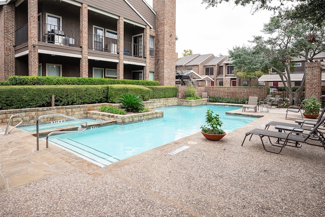 view of swimming pool with a patio area and a community hot tub