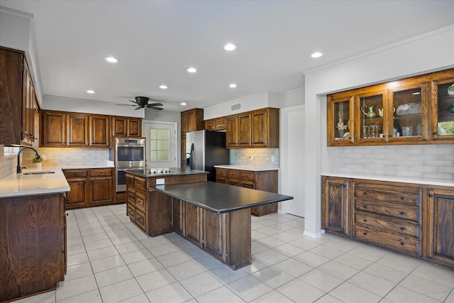 kitchen with appliances with stainless steel finishes, sink, backsplash, and a kitchen island