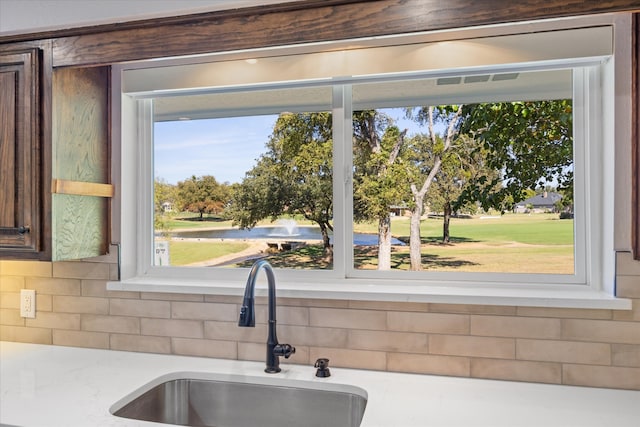 interior details with tasteful backsplash, dark brown cabinets, and sink