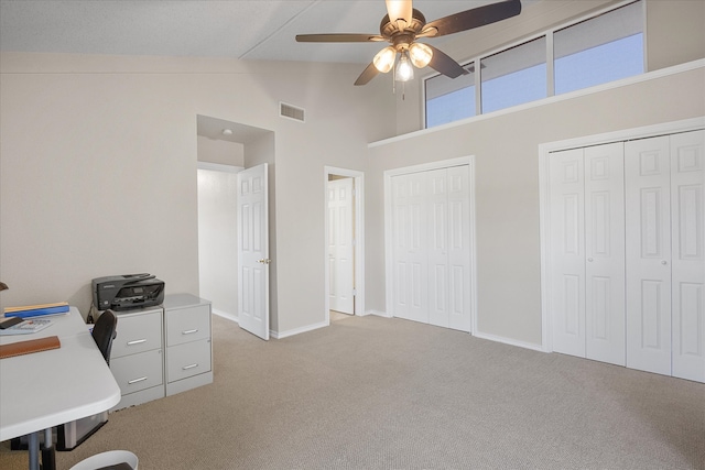 unfurnished office featuring light carpet, high vaulted ceiling, and ceiling fan