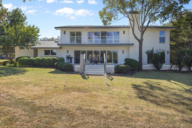 rear view of property with a yard and a balcony