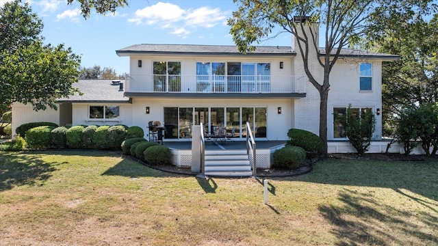 rear view of house with a yard and a balcony