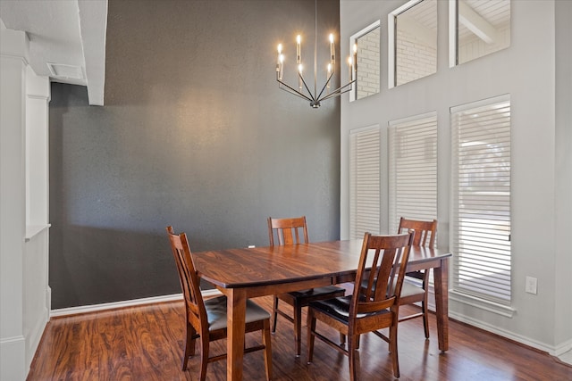 dining area with dark hardwood / wood-style floors, a chandelier, and a high ceiling