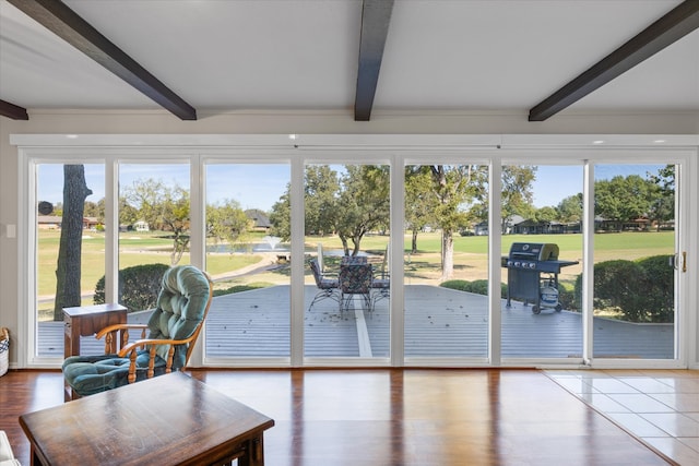 sunroom featuring beamed ceiling and a healthy amount of sunlight