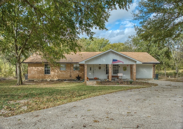 ranch-style house with covered porch, a front lawn, and a garage