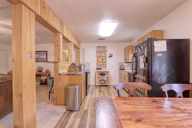 kitchen with light wood-type flooring and black fridge