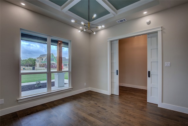 empty room featuring a wealth of natural light, coffered ceiling, a notable chandelier, and dark hardwood / wood-style flooring