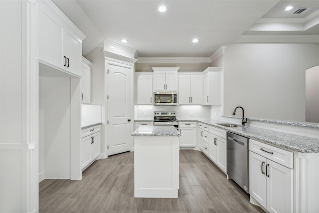 kitchen with sink, white cabinets, kitchen peninsula, stainless steel appliances, and light stone countertops