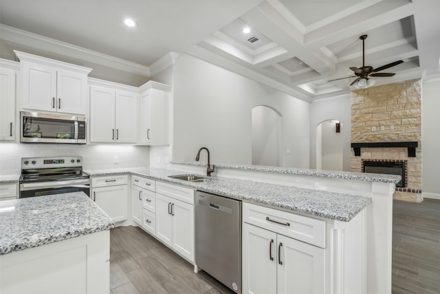 kitchen with kitchen peninsula, white cabinetry, sink, and appliances with stainless steel finishes