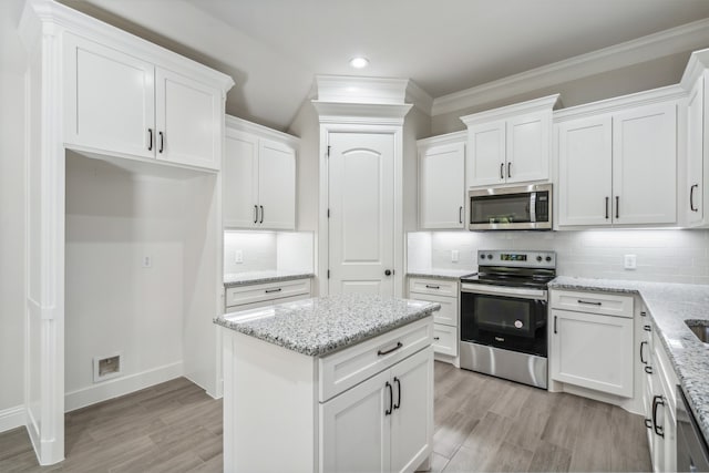 kitchen with white cabinetry, light stone countertops, backsplash, and appliances with stainless steel finishes